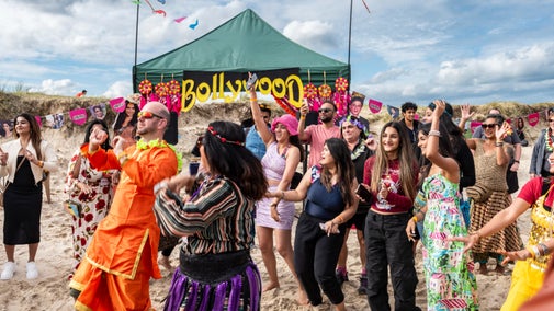 Visitors dancing at the Bollywood on the beach community event at Studland Bay, Dorset